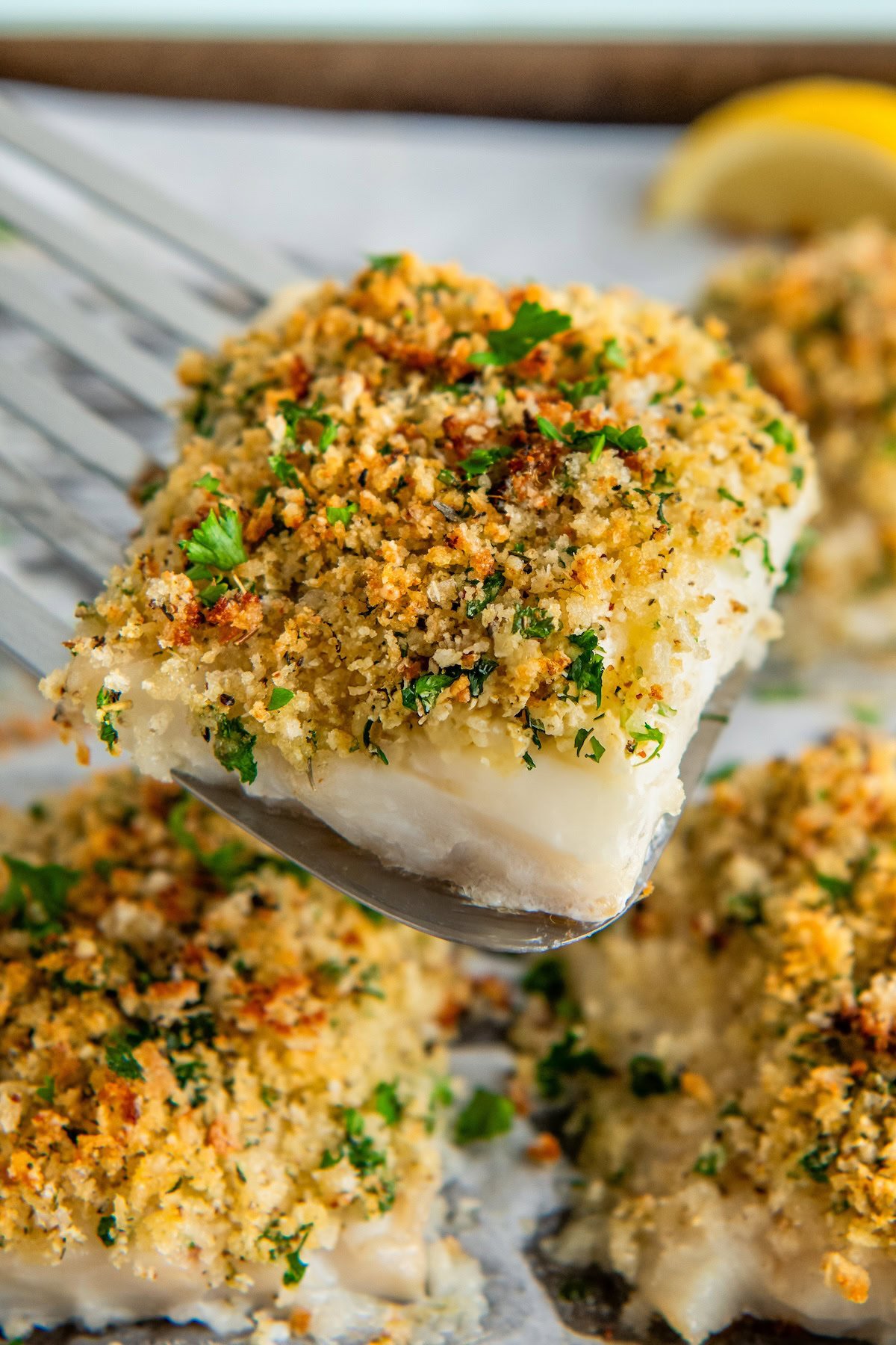 A serving of parmesan crusted cod is being lifted from a sheet pan.