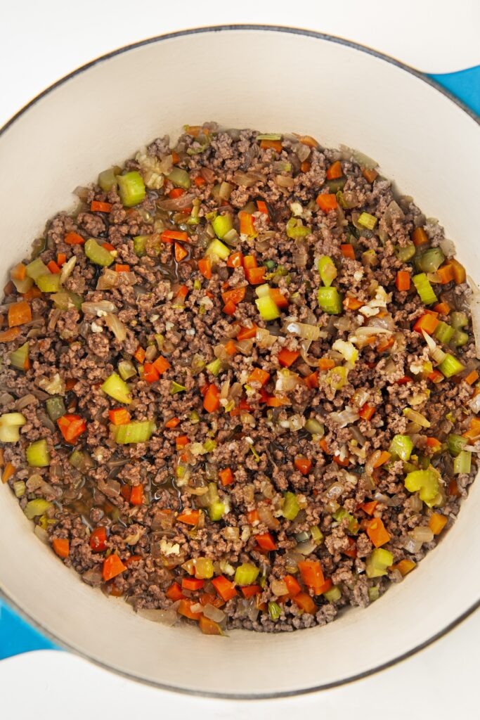 Meat and veggies are cooking in a large pot.