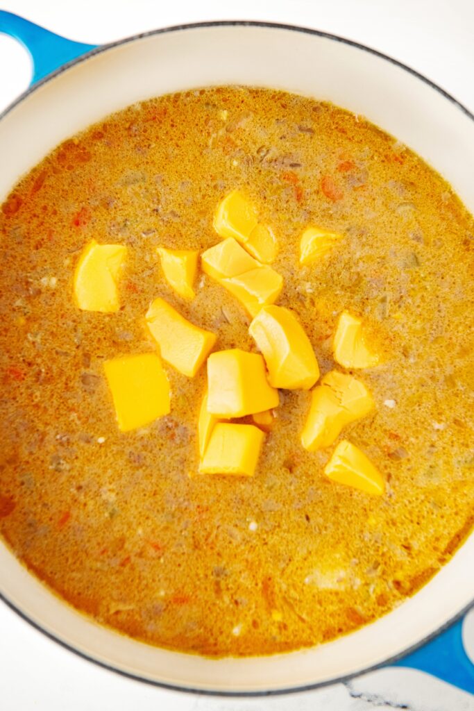 Golden potatoes are in the center of a large pot of cooking soup.