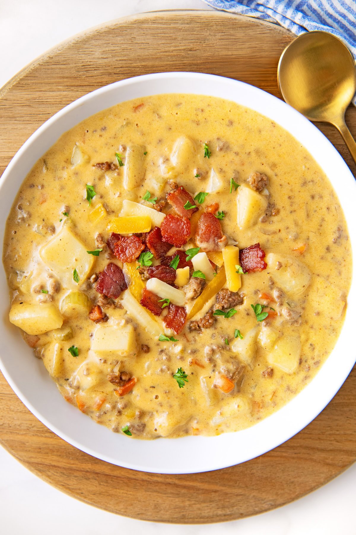 This one-pot Bacon Cheeseburger Soup recipe combines all the flavors of a burger into a hearty and creamy soup with lots of hidden veggies! A bowl full of cheeseburger soup is topped with bacon, cheese, and chives.