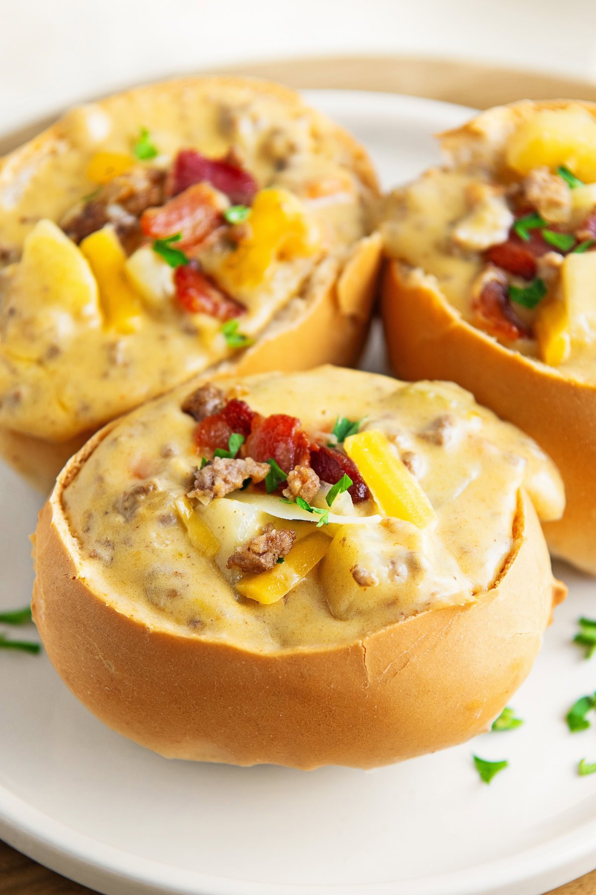 Several full bowls of soup are garnished with bacon, chives, and cheese.
