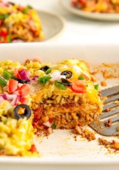 A sliced serving of burrito casserole in a large white baking dish.