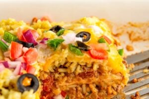 A sliced serving of burrito casserole in a large white baking dish.