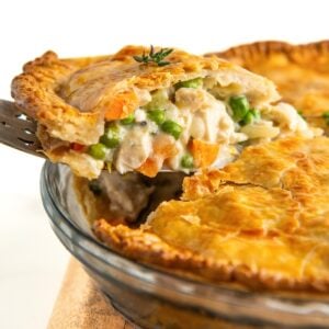 A large slice of chicken pot pie is being lifted from the pie dish.