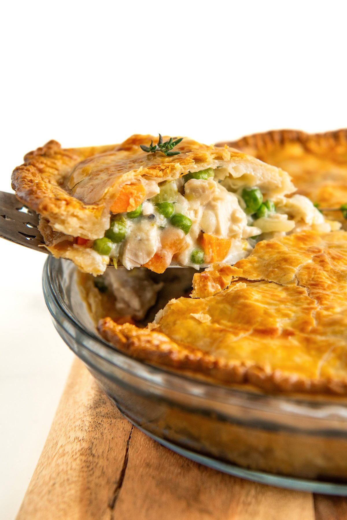 A large slice of chicken pot pie is being lifted from the pie dish.