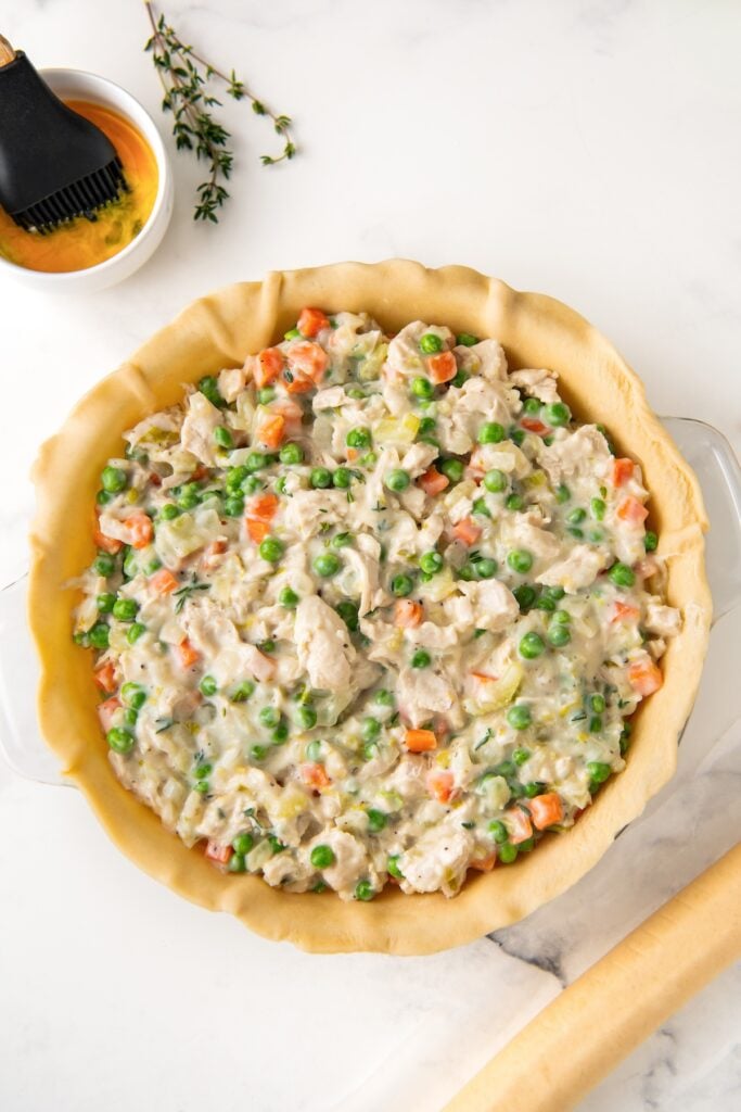 A pie dish is filled with pie crust and creamy chicken pot pie filling.