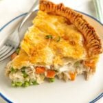 A thick slice of pot pie is presented on a round white plate.