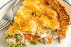 A thick slice of pot pie is presented on a round white plate.