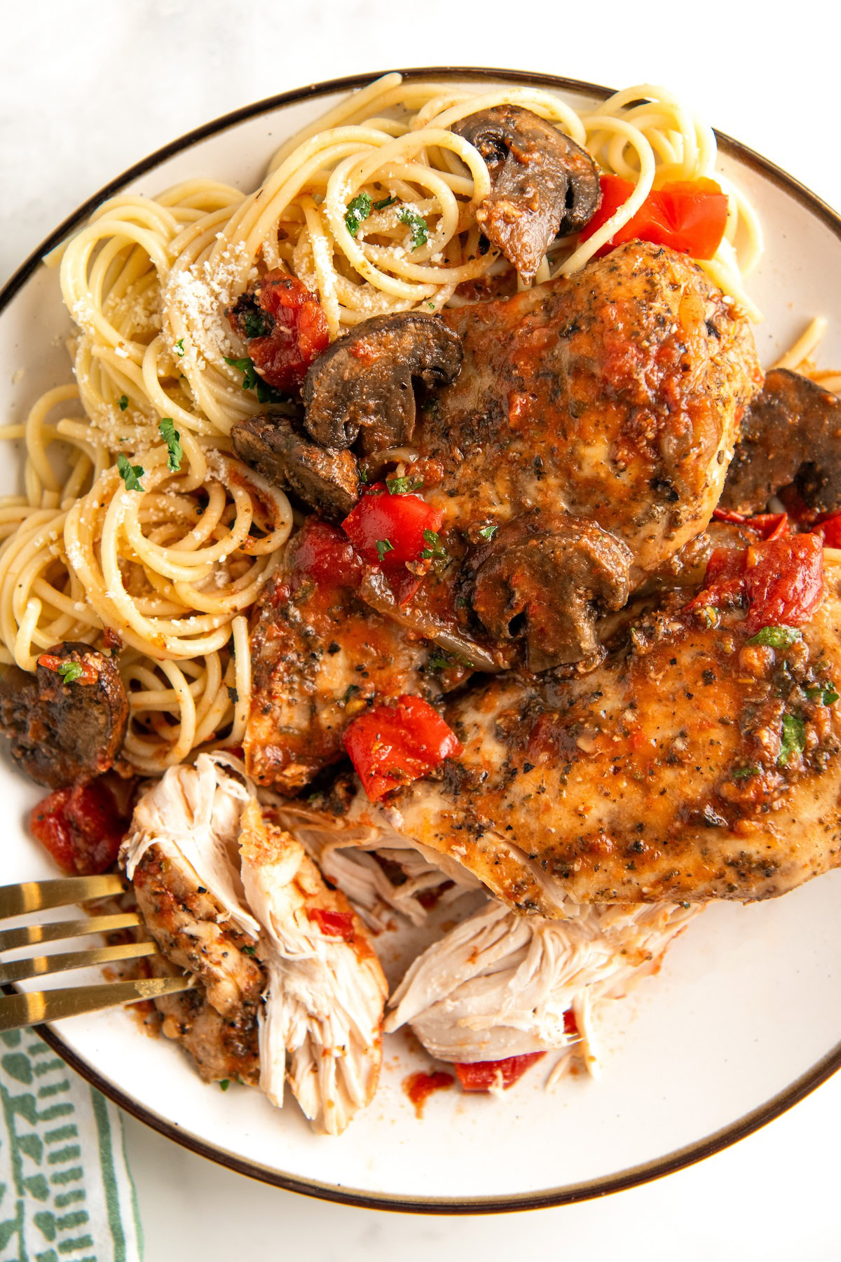 A fork is piercing a piece of crockpot chicken cacciatore and removing it from the plate.