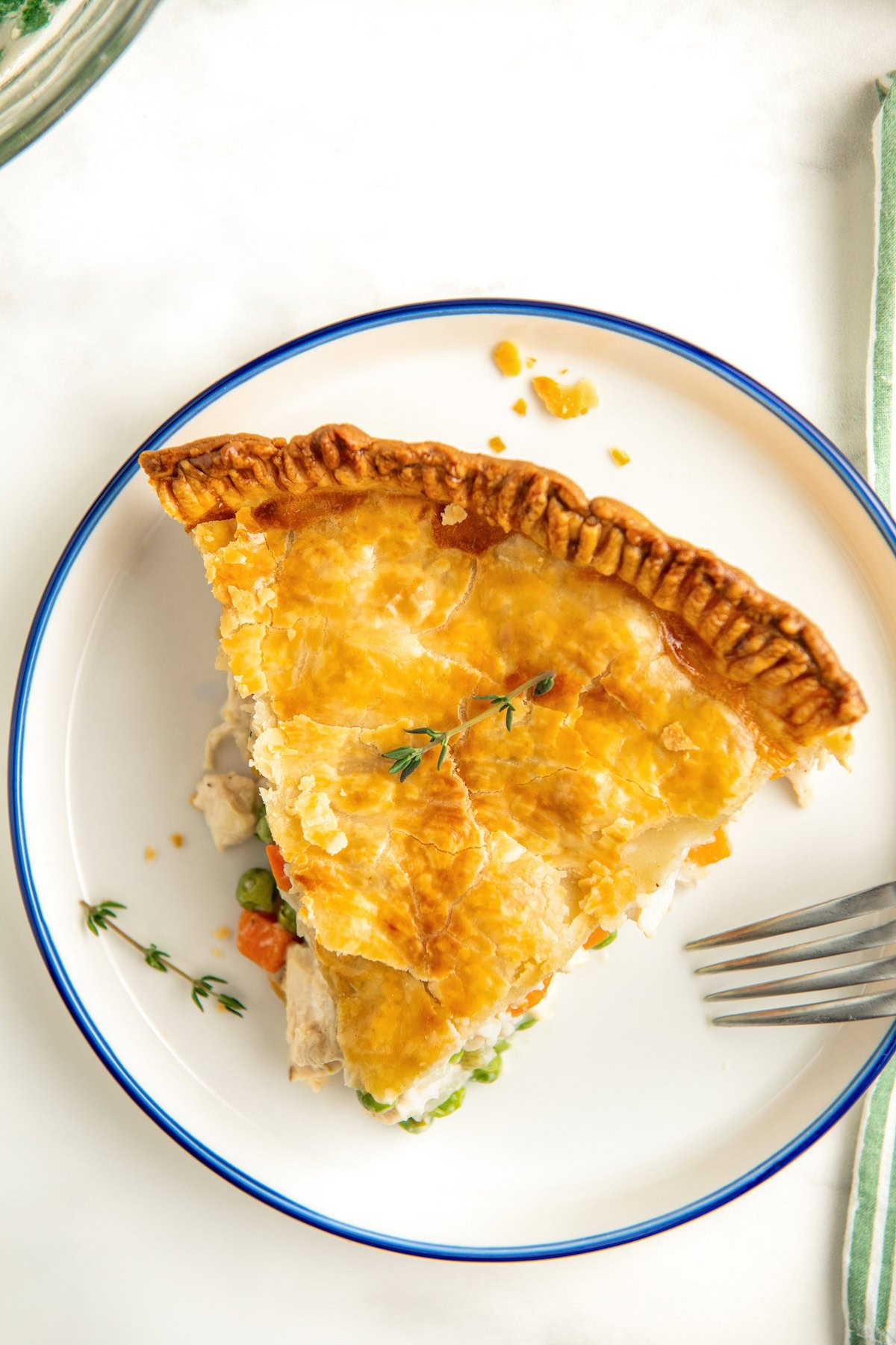 A slice of golden brown chicken pot pie is placed on a white plate.