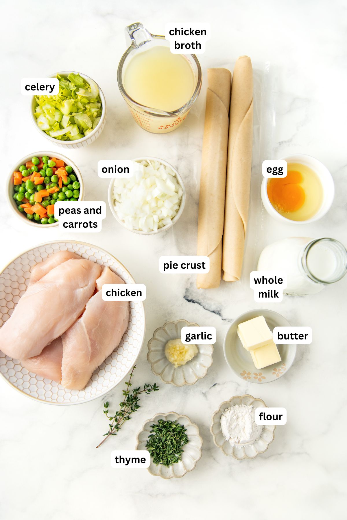 Ingredients for easy chicken pot pie recipe in order from top to bottom: chicken broth, celery, peas and carrots, onion, pie crust, egg, chicken, garlic, butter, thyme, flour.