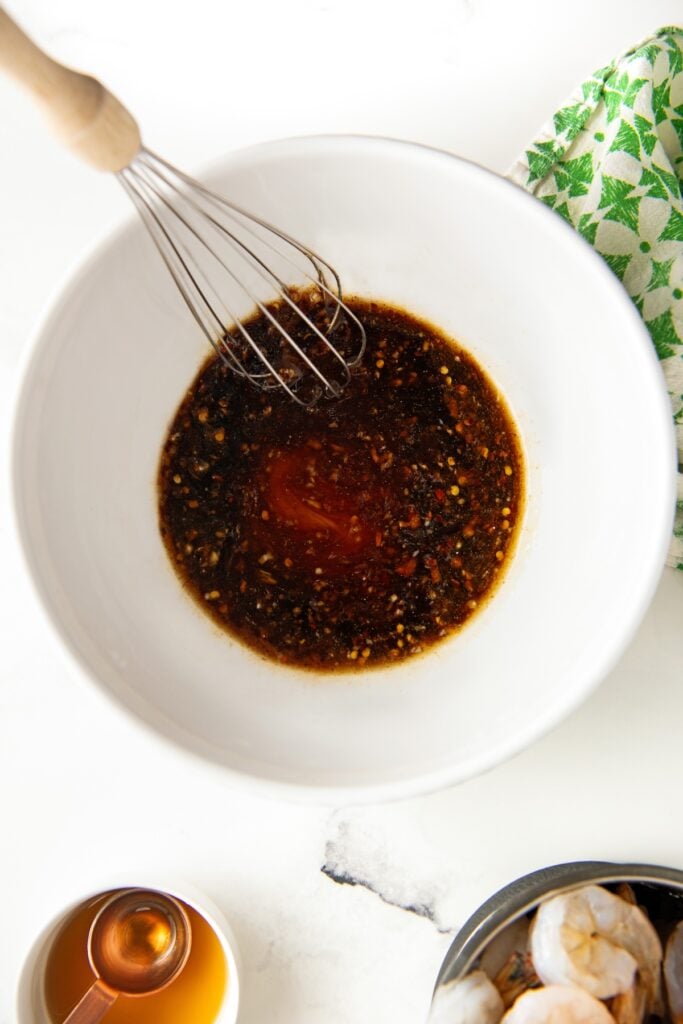 Sauce is being whisked in a large white mixing bowl.