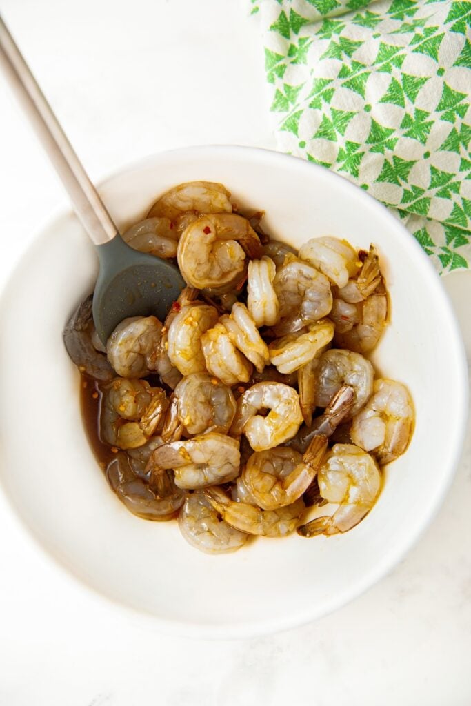 Raw shrimp are being tossed in homemade sauce.