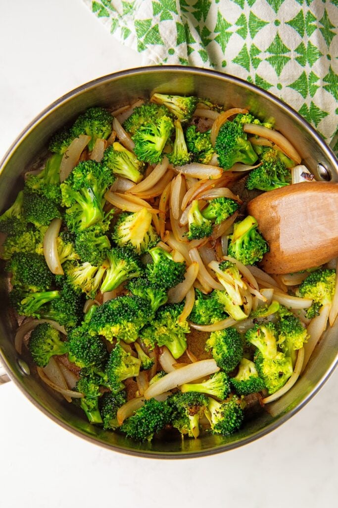 Vegetables are cooking in a large skillet.