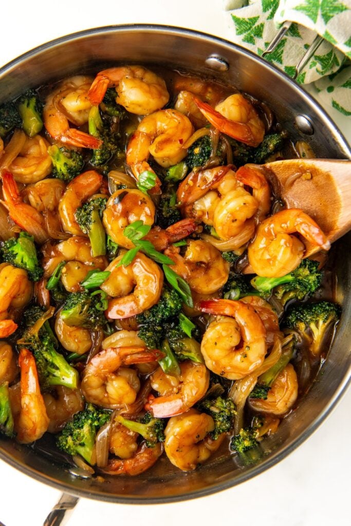 Shrimp and veggies are being cooked in a skillet.