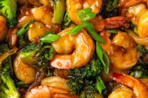 Chopped green onions are sprinkled on top of asian shrimp and broccoli.