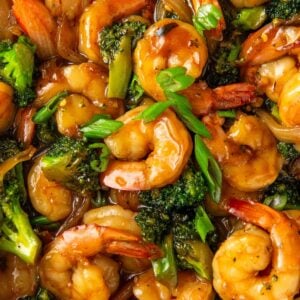 Chopped green onions are sprinkled on top of asian shrimp and broccoli.