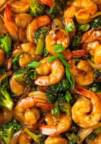 Chopped green onions are sprinkled on top of asian shrimp and broccoli.