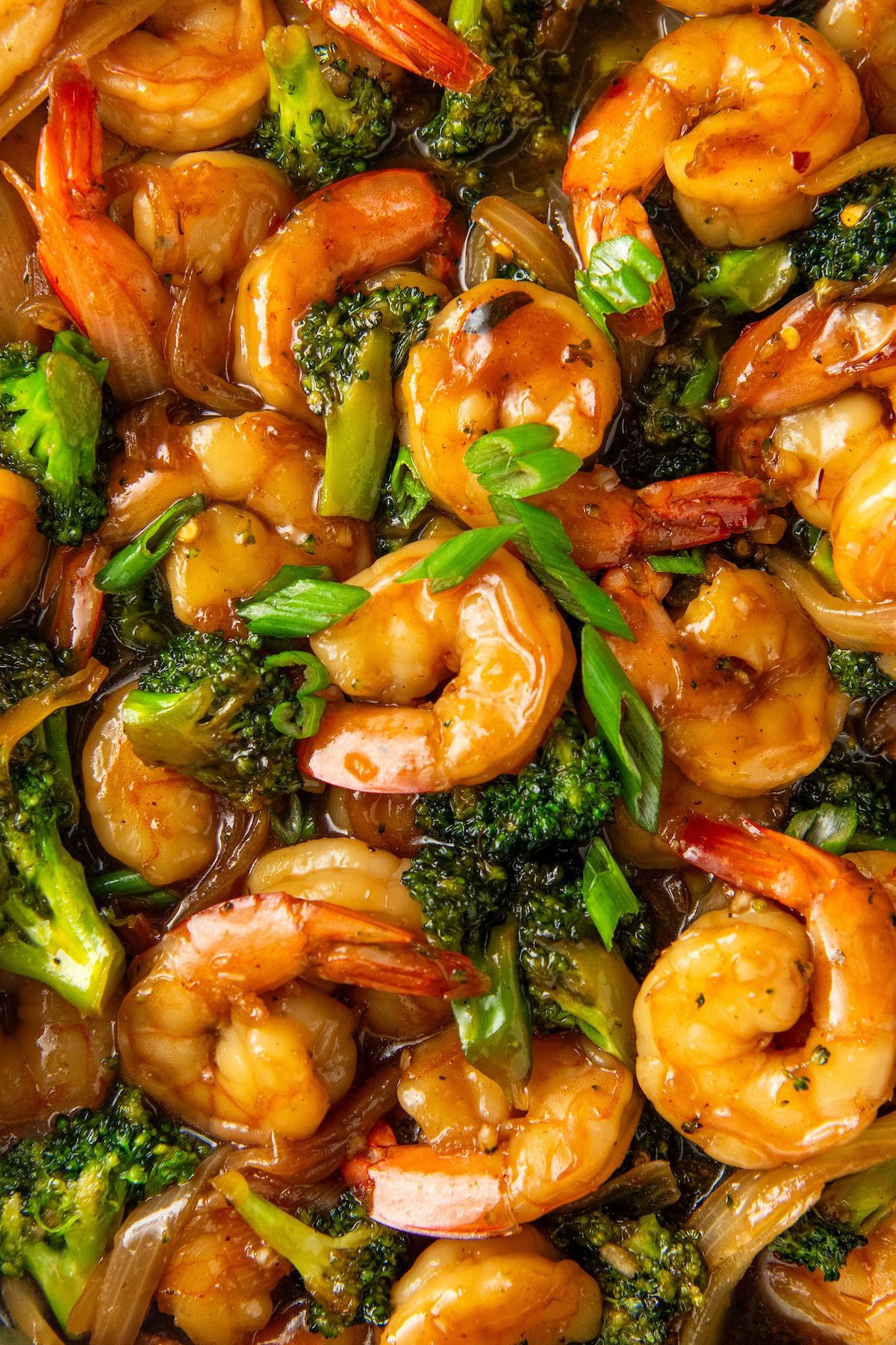 Chopped green onions are sprinkled on top of asian shrimp and broccoli.