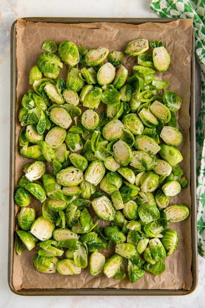 Uncooked sprouts are spread on a prepared baking sheet.