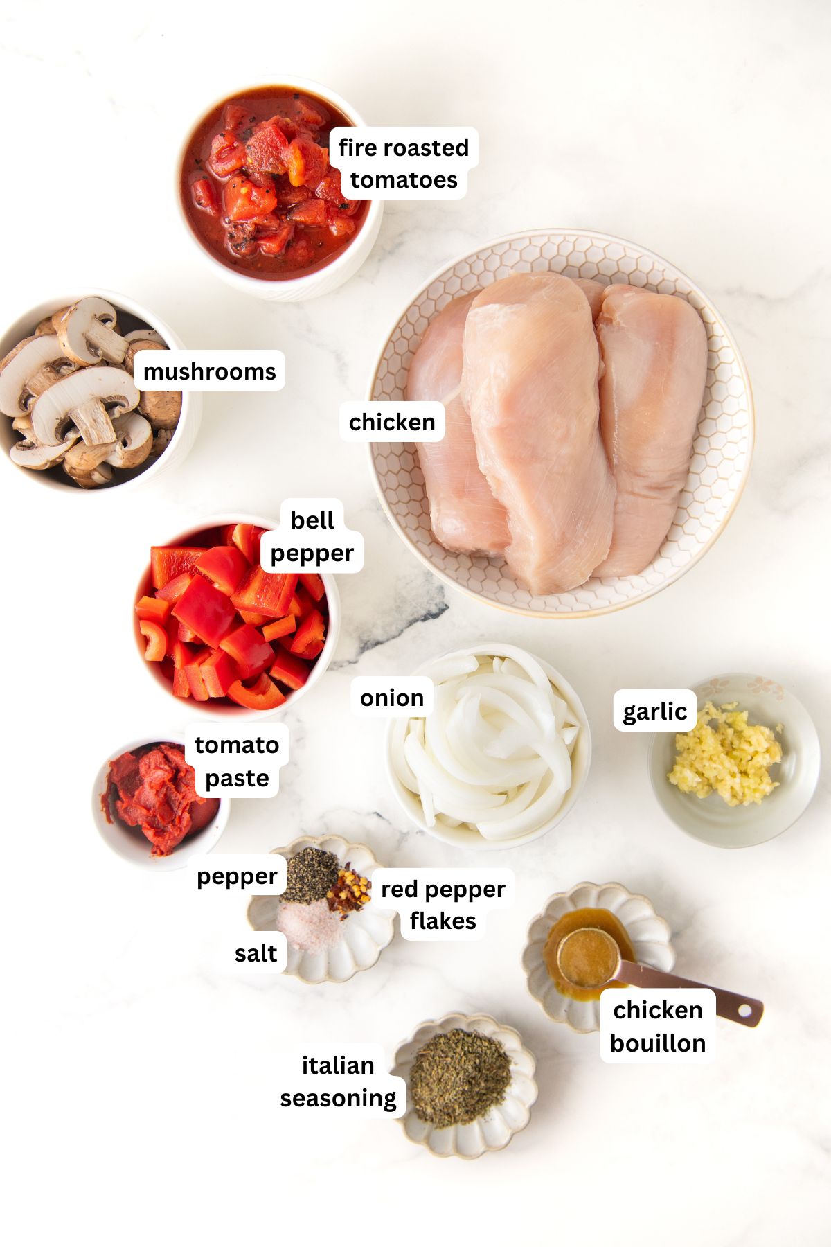 Ingredients for slow cooker chicken cacciatore recipe in order from top to bottom: fire roasted tomatoes, mushrooms, chicken, bell pepper, tomato paste, onion, garlic, pepper, salt, red pepper flakes, chicken bouillon, Italian seasoning.