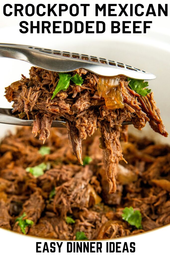 A serving of crockpot Mexican shredded beef is being lifted from a bowl with tongs. The beef is garnished with cilantro.