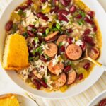 A slice of cornbread is served with a bowl of cajun soup.