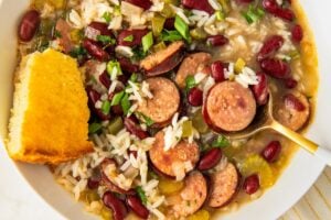 A slice of cornbread is served with a bowl of cajun soup.