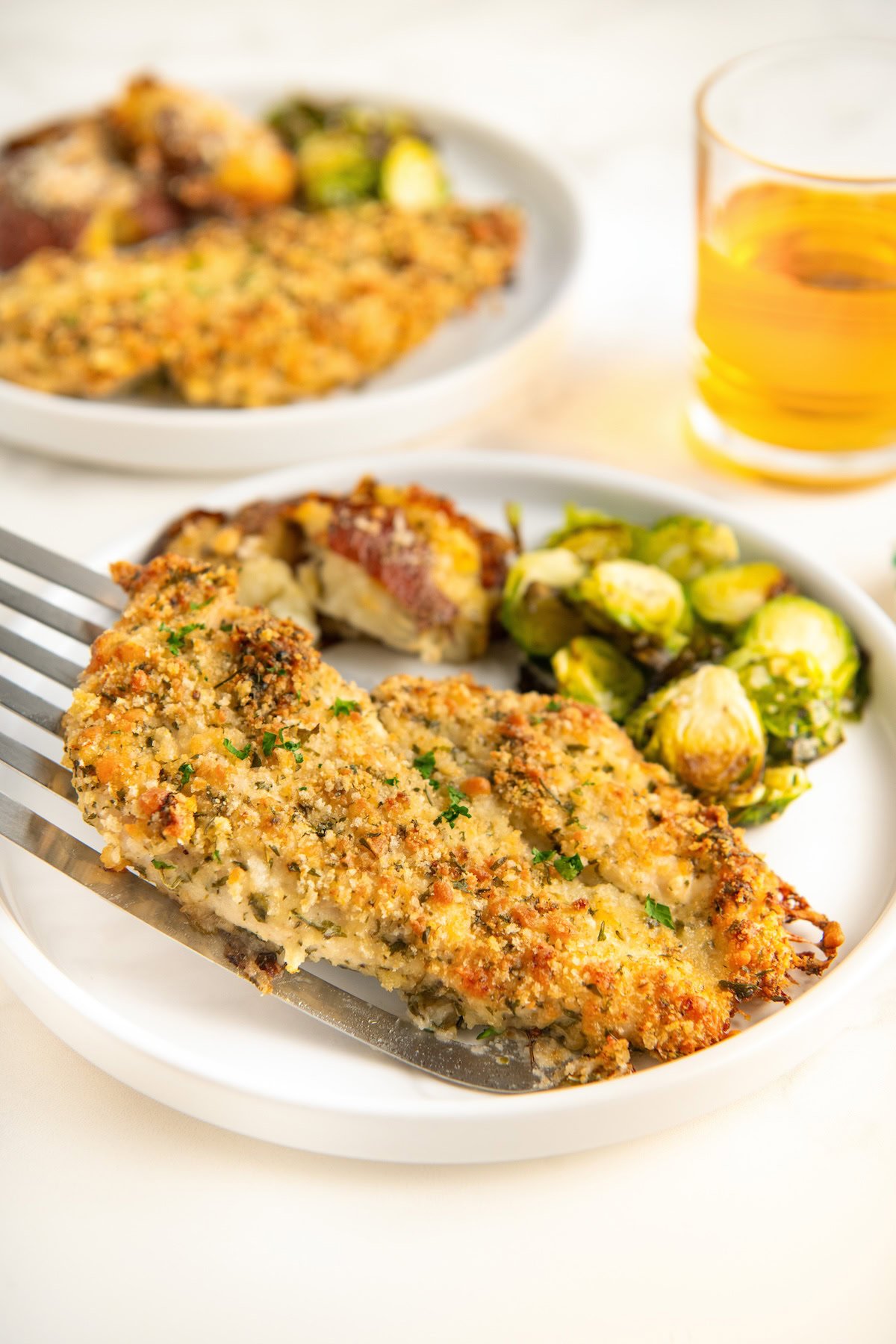 Crispy chicken breast plated beside roasted brussels sprouts.