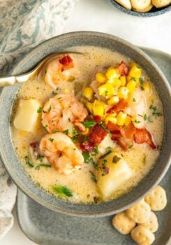 Shrimp and corn chowder is presented in a bowl with a spoon.