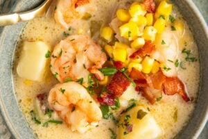 Shrimp and corn chowder is presented in a bowl with a spoon.