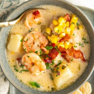Shrimp and corn chowder is presented in a bowl with a spoon.