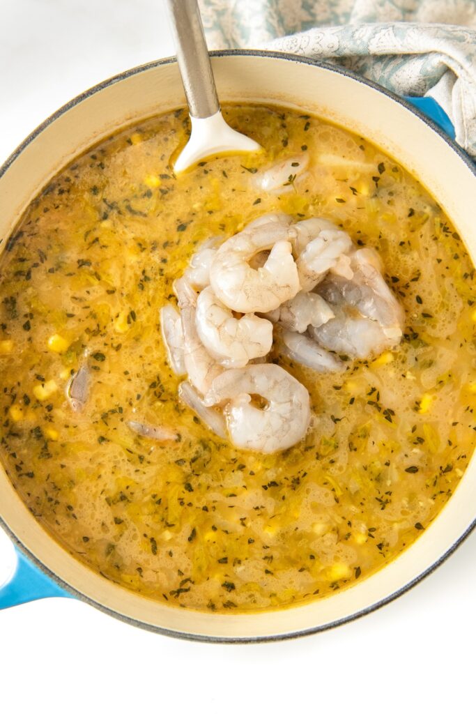 Shrimp has been added to a pot filled with chowder.