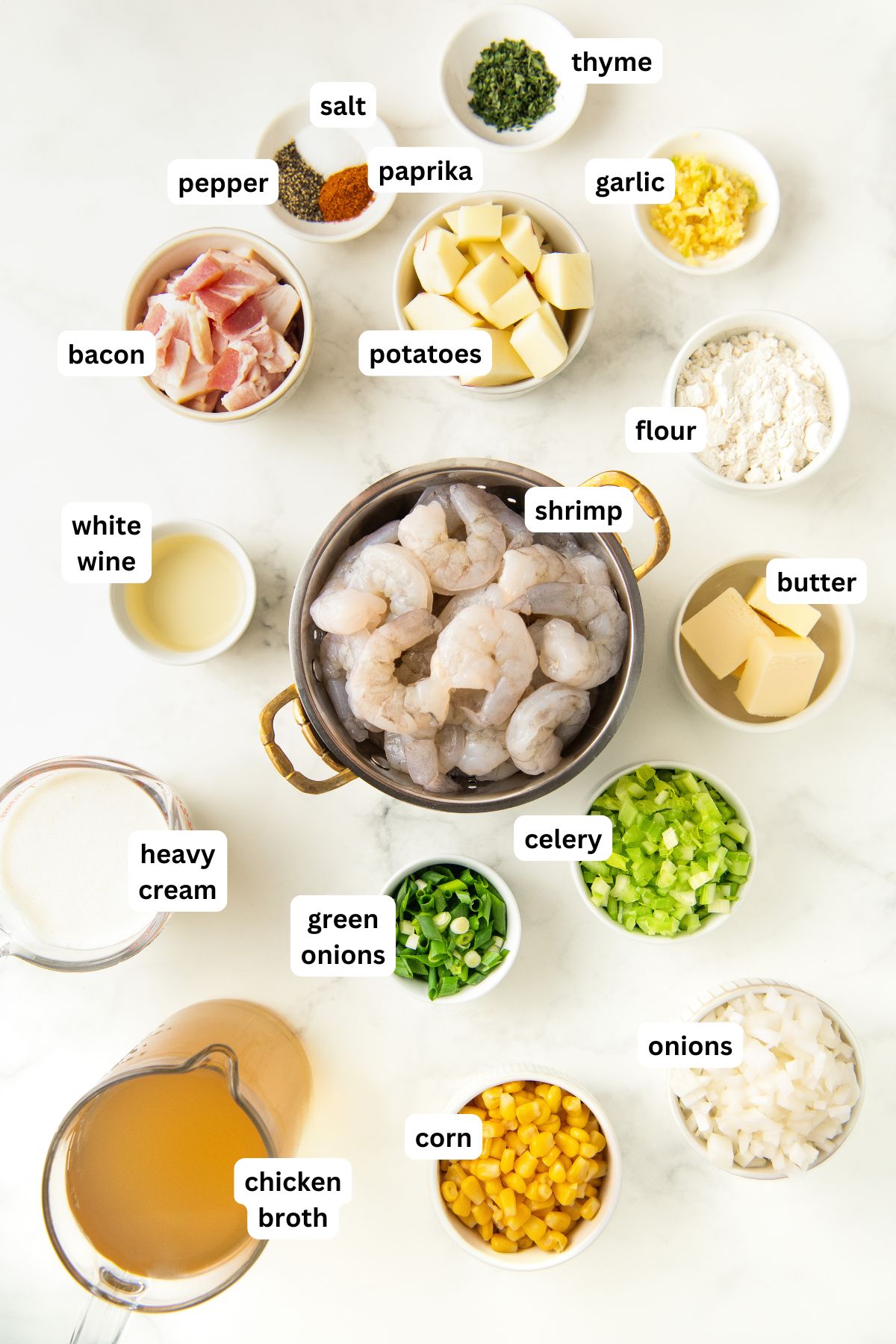 Ingredients for shrimp and corn chowder recipe in order from top to bottom: salt, pepper, paprika, thyme, garlic, potatoes, bacon, white wine, shrimp, flour, butter, celery, green onions, heavy cream, chicken broth, corn, and onions.