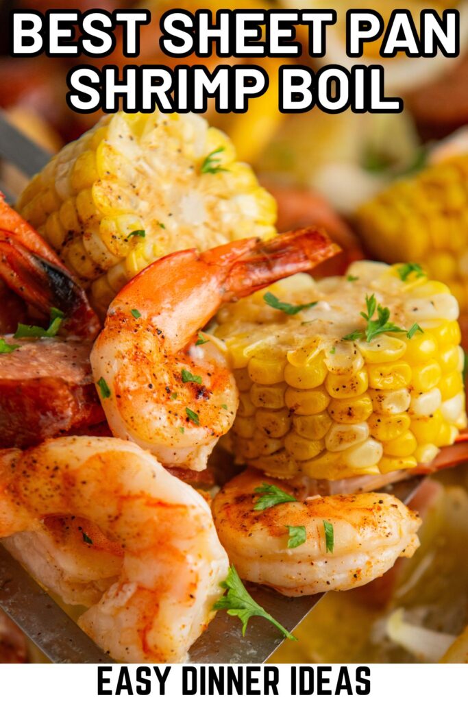 Close-up of a sheet pan shrimp boil featuring cooked shrimp, corn on the cob, and sausage slices, garnished with chopped herbs.