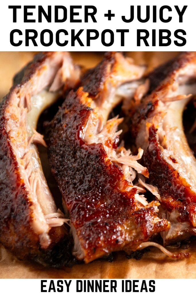Close-up of three crockpot ribs with a glazed, caramelized surface and tender meat, placed on a wooden surface.