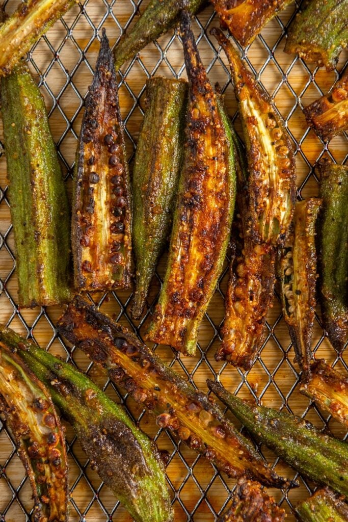 Close-up of charred and crispy air fryer okra halves arranged on a wire rack.