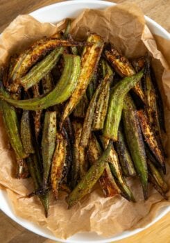 A bowl lined with brown parchment paper filled with air fryer, seasoned and slightly charred, sitting on a wooden surface.