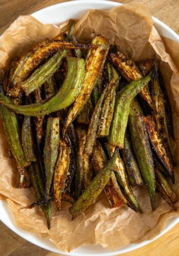 A bowl lined with brown parchment paper filled with air fryer, seasoned and slightly charred, sitting on a wooden surface.