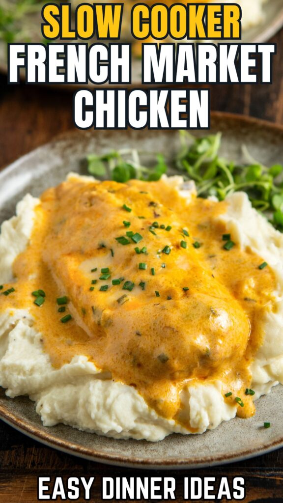 A plate of mashed potatoes topped with a piece of crockpot chicken covered in a creamy orange sauce, garnished with chopped chives.