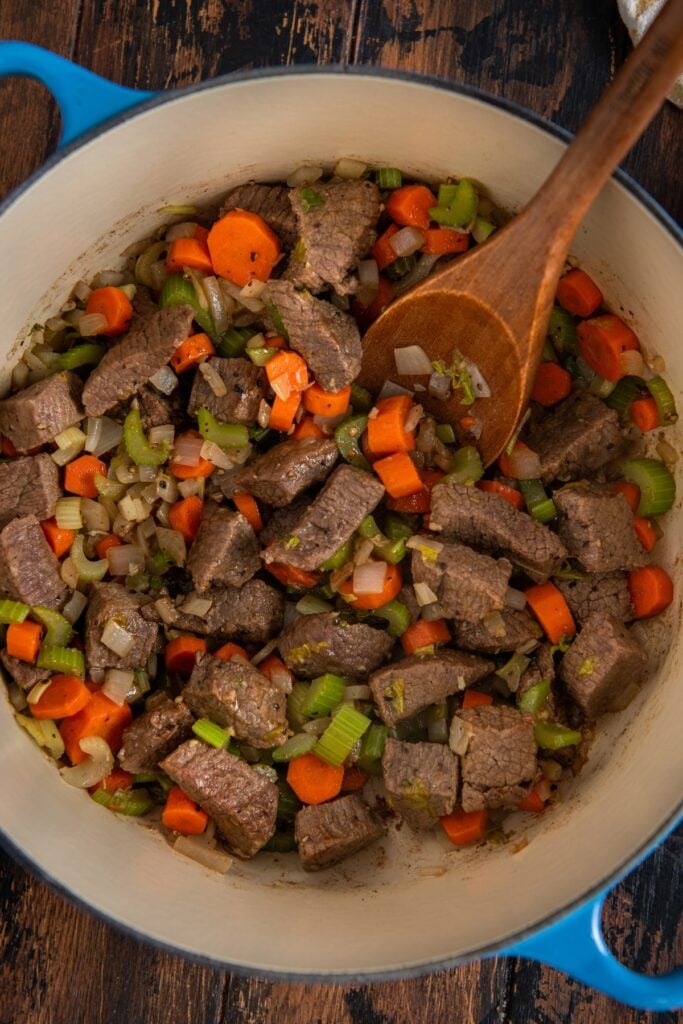 Made easy in one-pot, Beef Barley Soup is loaded with tender beef, chewy pearl barley, and lots of vegetables in a rich and savory broth. A pot filled with chunks of browned beef, sliced carrots, celery, and onions being stirred with a wooden spoon.