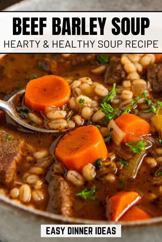 Close-up of beef barley soup with chunks of beef, sliced carrots, barley, and parsley in a broth.