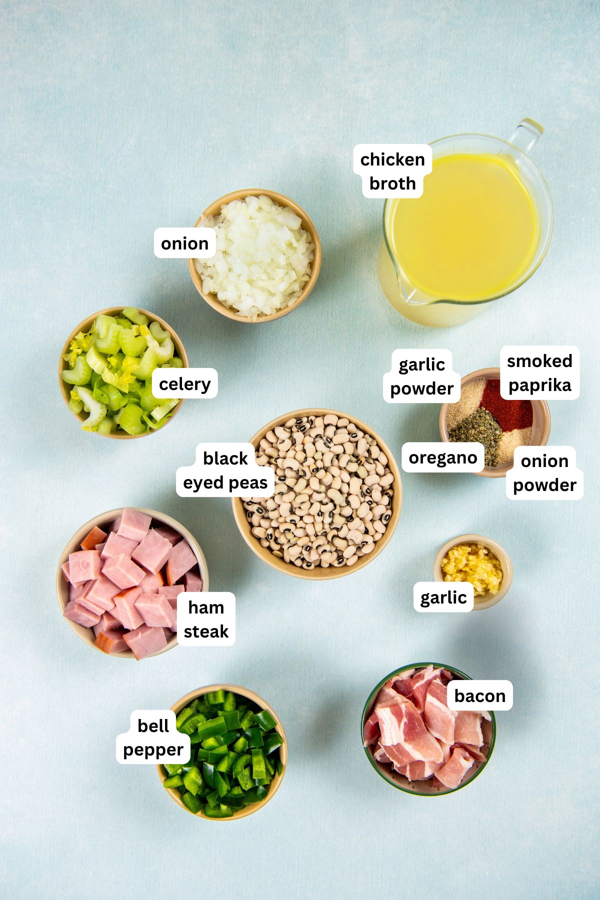 Slowly simmered in a rich and smoky broth, these Southern Black Eyed Peas are insanely flavorful and tender as can be! Labeled ingredients for black eyed peas recipe, including chopped onion, celery, garlic, ham steak, bell pepper, bacon, black eyed peas, chicken broth, garlic powder, oregano, smoked paprika, and onion powder.