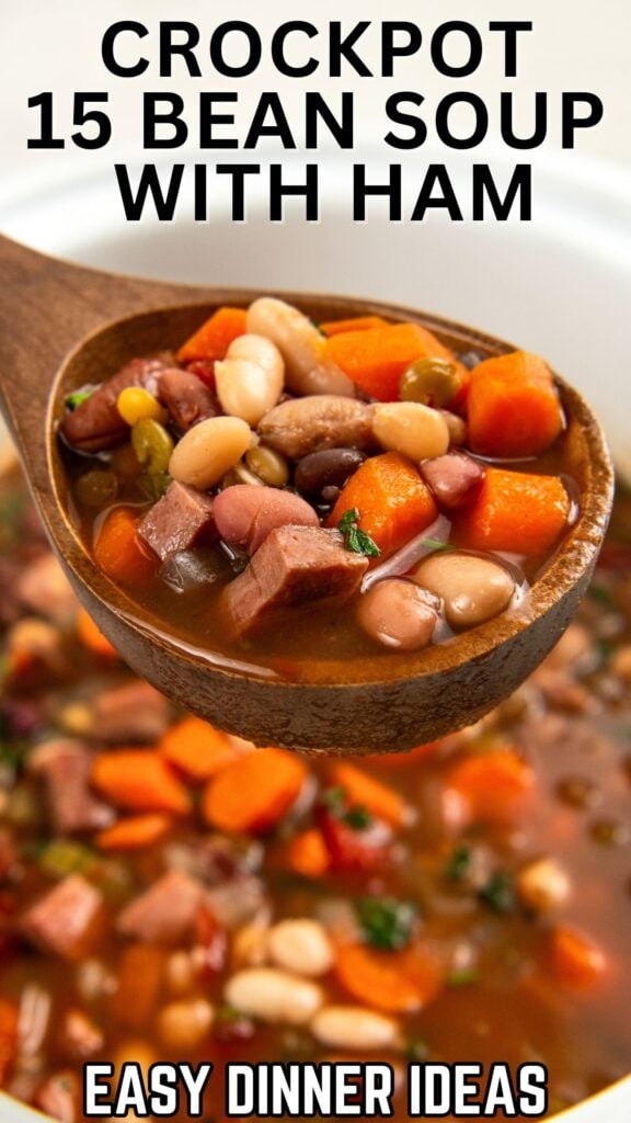 A wooden spoon holds a hearty scoop of 15 bean soup with ham, carrots, and vegetables above a pot of soup.