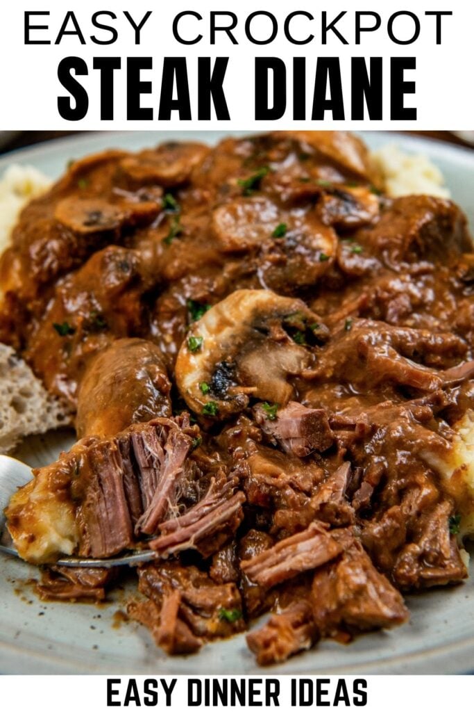 A plate of slow-cooked Steak Diane topped with rich brown gravy and mushrooms, served over mashed potatoes, with a fork pulling apart tender pieces of beef.