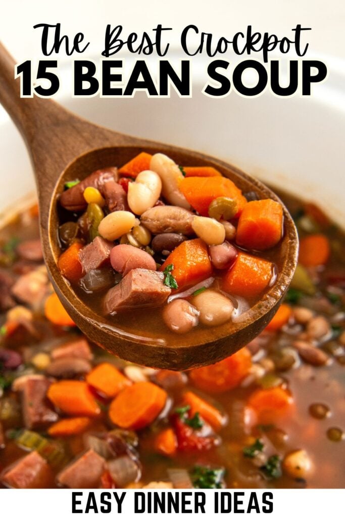 A wooden spoon holds a serving of 15 bean soup with diced carrots and ham over a pot of the same soup.