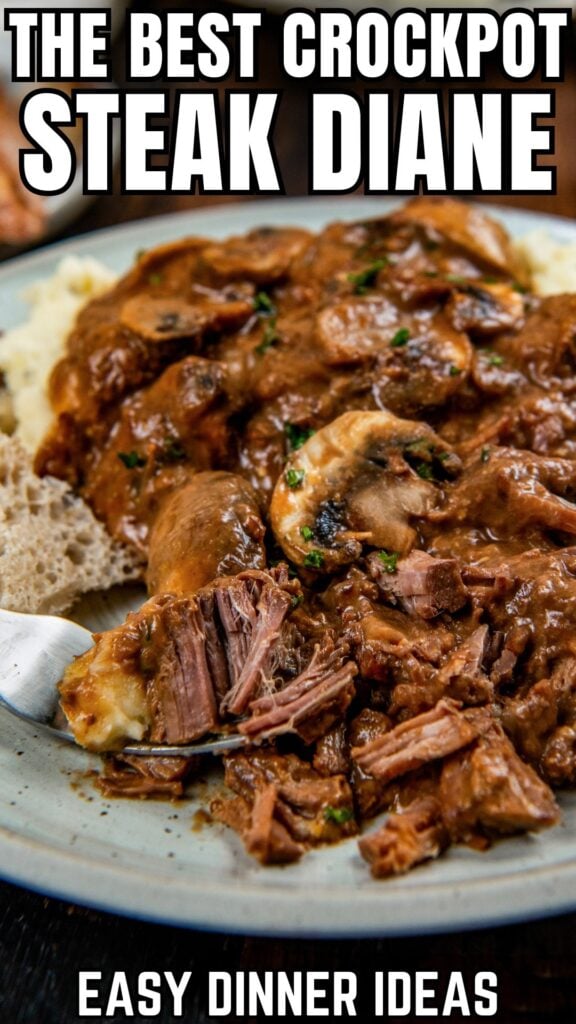 A plate of Crockpot Steak Diane with tender beef, mushrooms, and rich gravy, served with mashed potatoes and bread.