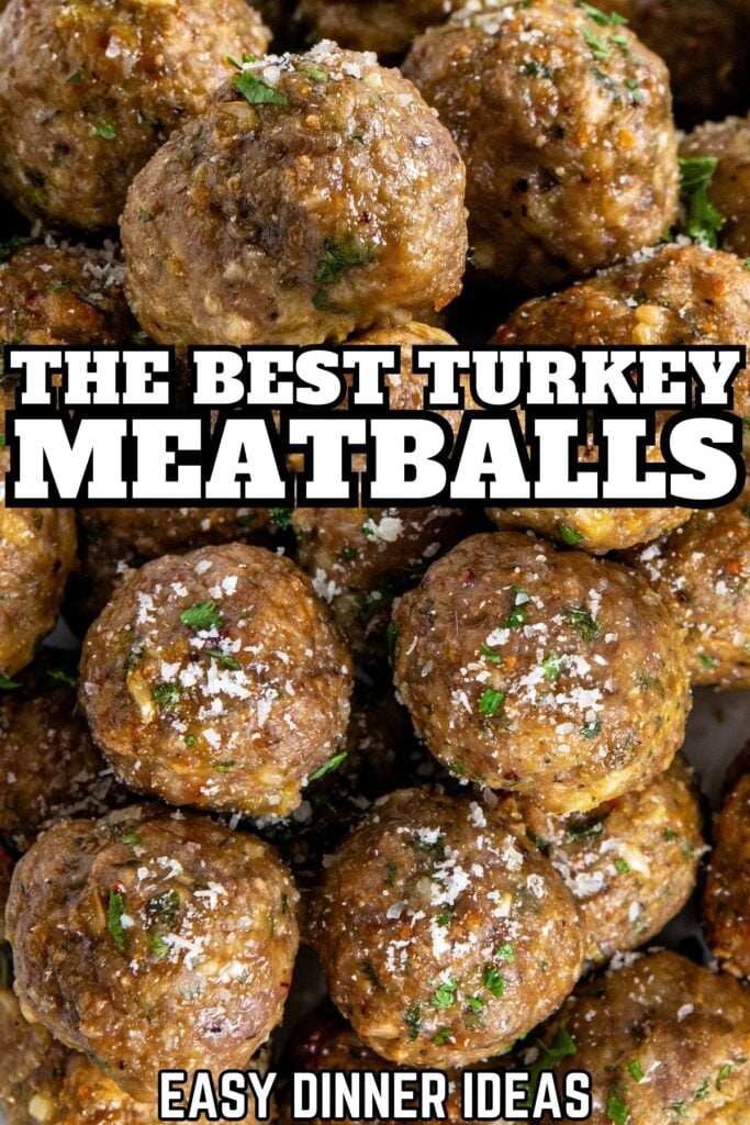 Close-up of several cooked ground turkey meatballs, garnished with fresh herbs and grated Parmesan cheese.