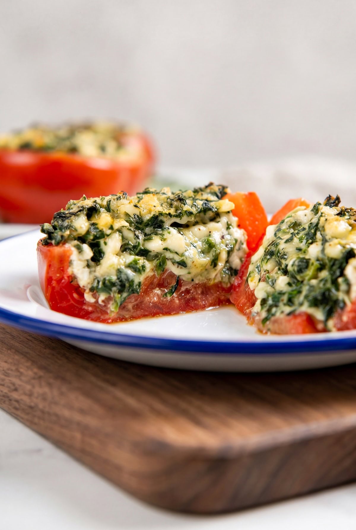 These stuffed tomatoes are ready in 30 minutes with a creamy spinach and cheese filling. Low carb, high protein, and seriously delicious! A close-up of a stuffed tomato filled with a creamy spinach and cheese mixture, the tomato is cut in half to show the filling.
