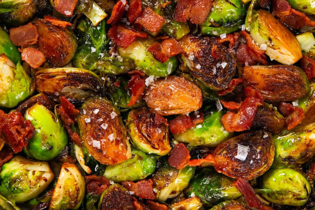 Hot Honey Brussels Sprouts with crispy bacon, caramelized sprouts, and a sweet-spicy honey drizzle. One skillet, ready in 25 minutes! Hot honey Brussels sprouts with crispy browned edges are mixed with pieces of cooked bacon and sprinkled with crushed red pepper and flaky sea salt.